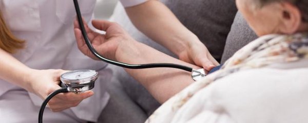 Frau macht eine Blutdruckmessung beim Arzt